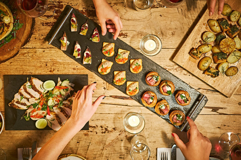 An overhead shot looking down at a wooden table filled with seasonal party food.