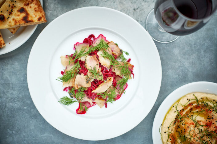 Fish carpaccio and glass of red wine served with colourful garnishes