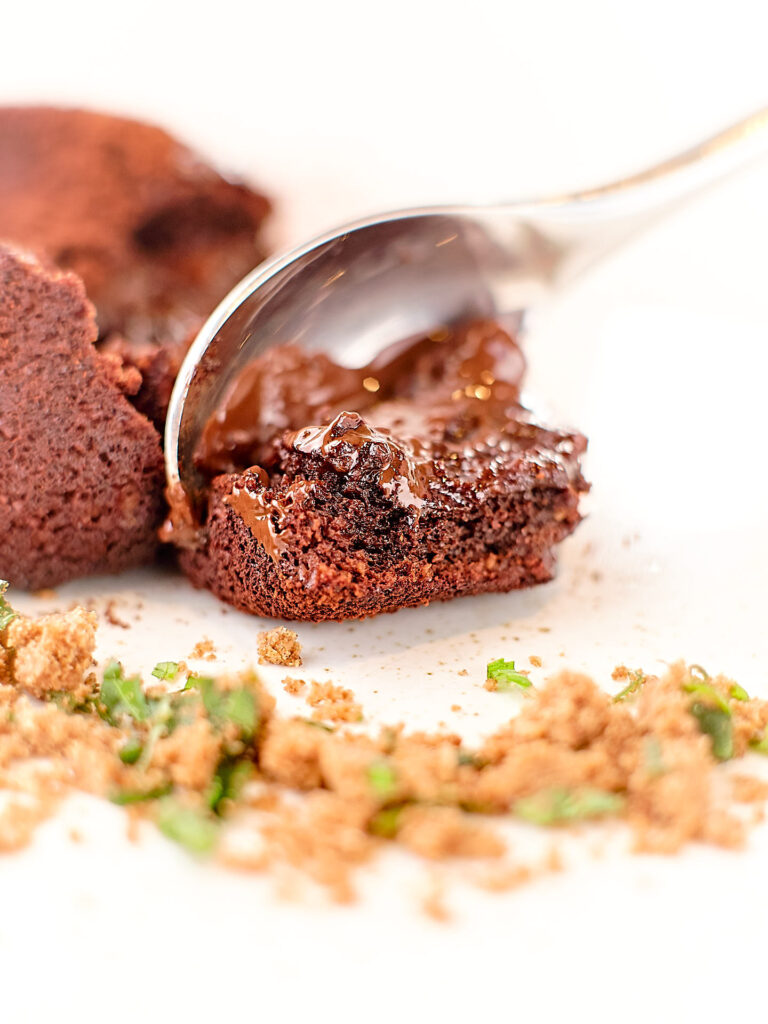 A melting chocolate desert with a soft filling spilling out onto the spoon.